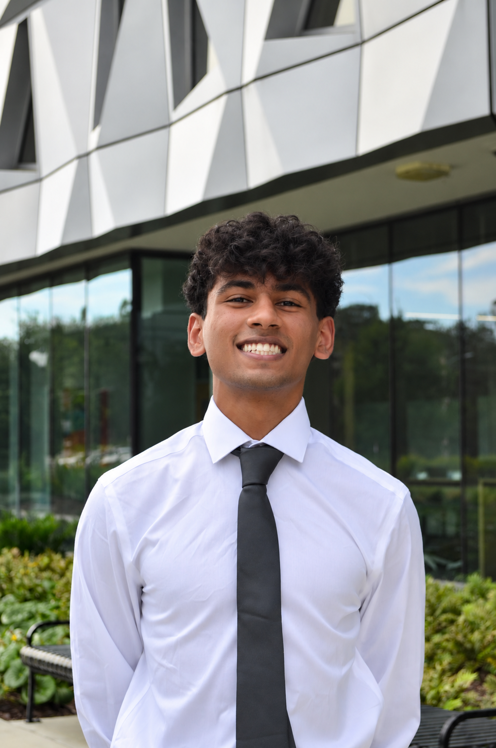 Rishi smiling outside a campus building