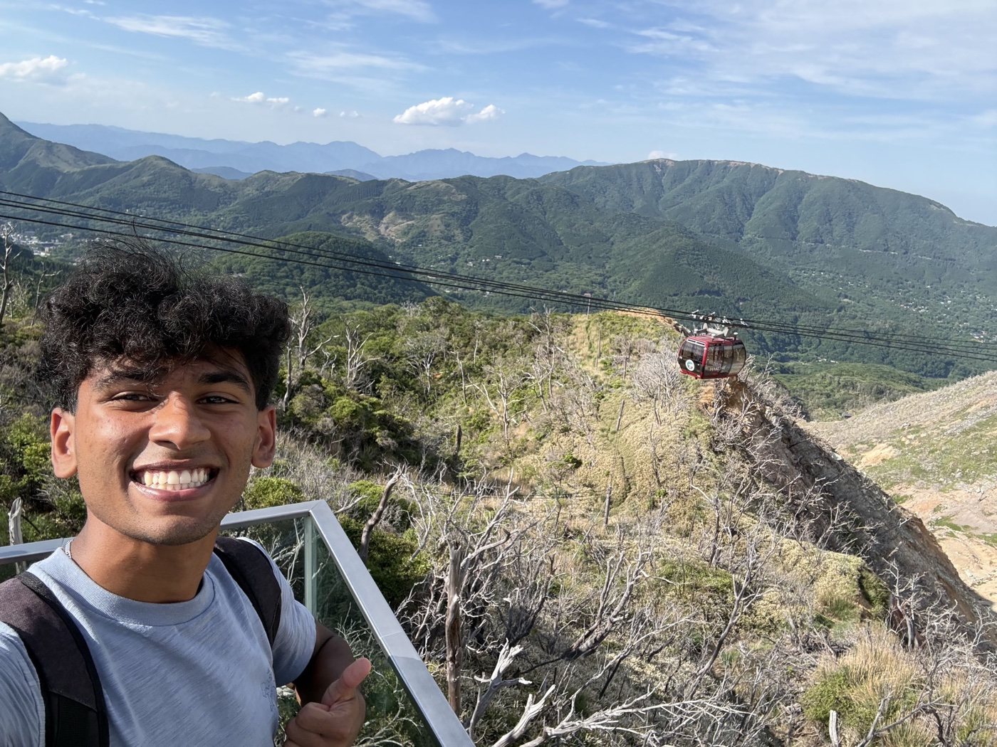 Rishi smiling at a mountain viewpoint in Japan